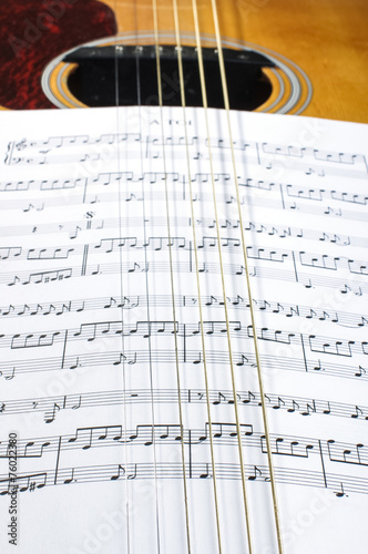 Sheet music notes under six guitar strings
