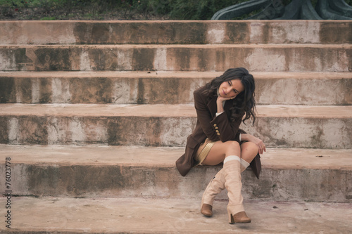 Beautiful young woman sitting on concrete steps