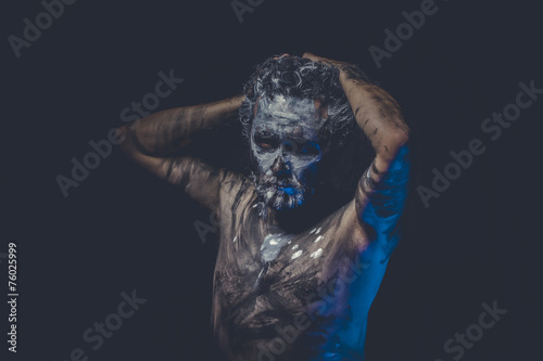 aggression, naked man covered with paint and mud skin
