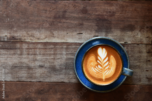 Fotografi cup of latte art coffee on wooden background