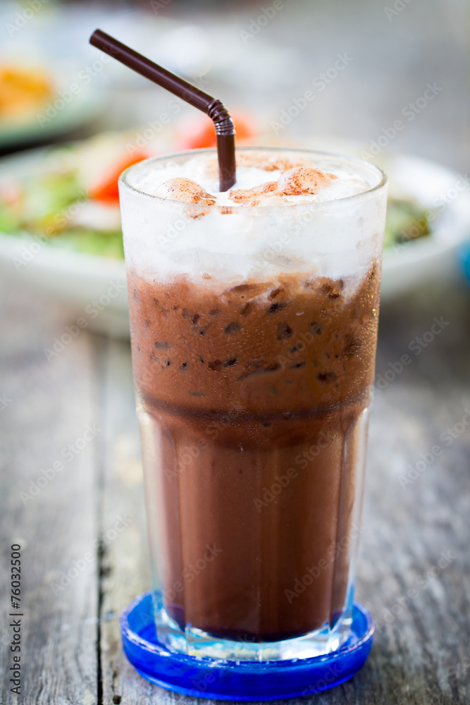 Iced milk chocolate with straw on wood table Iced milk chocolate with straw on wood table