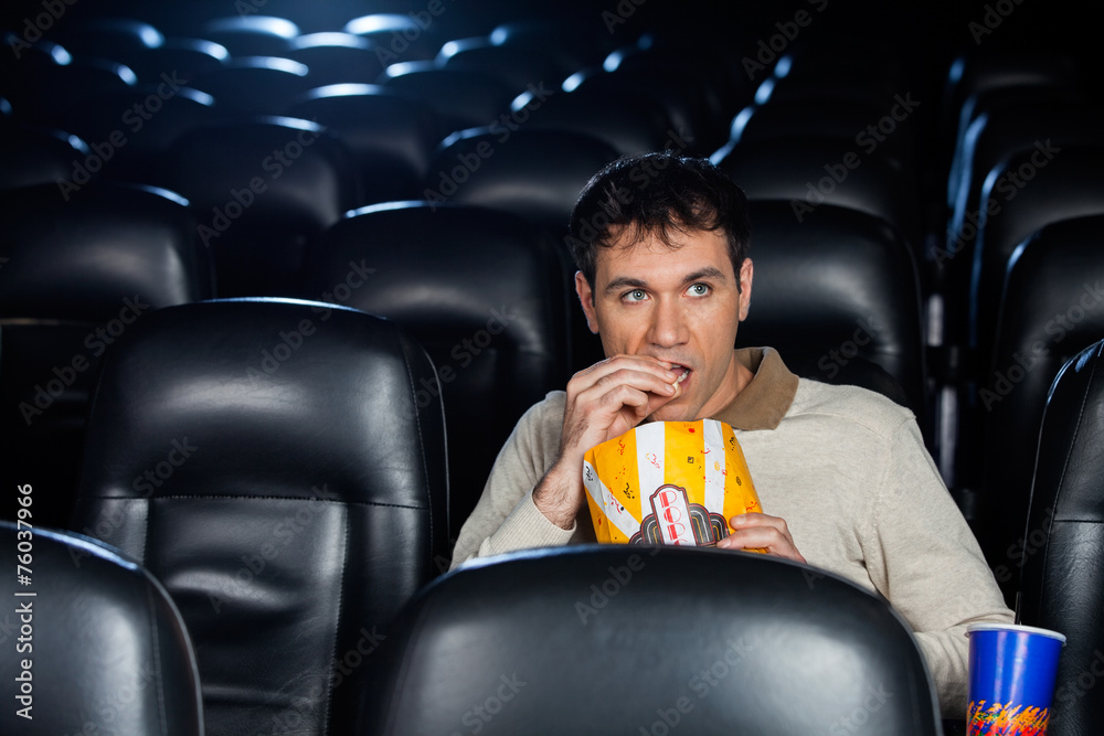 Fototapeta premium Man Eating Popcorn While Watching Movie In Theater