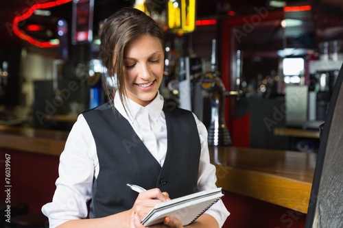 Happy barmaid writing in notepad