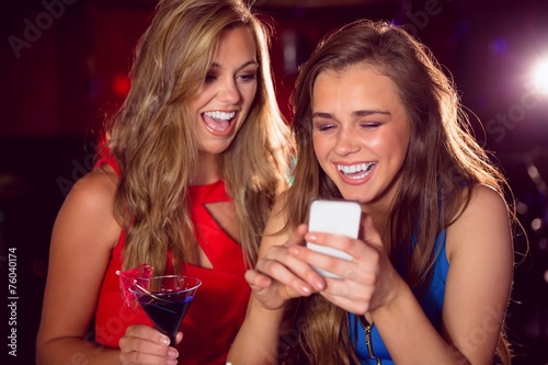 Pretty friends looking at smartphone together