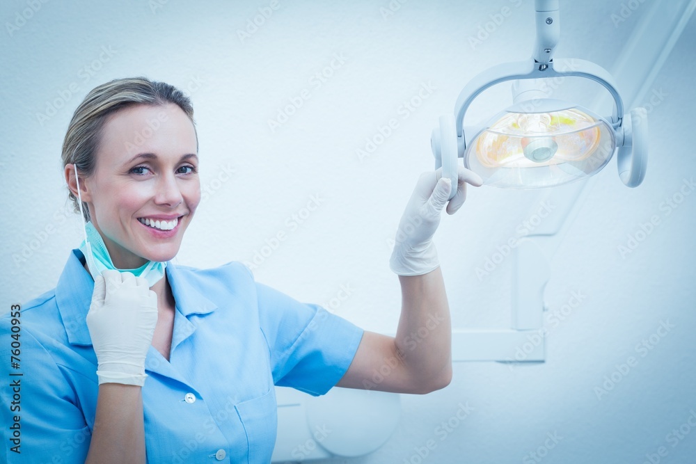 Smiling female dentist adjusting light - obrazy, fototapety, plakaty 