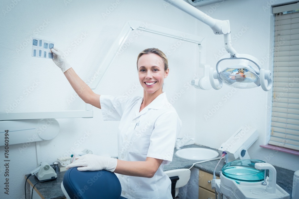 Smiling female dentist looking at x-ray Smiling female dentist looking at x-ray