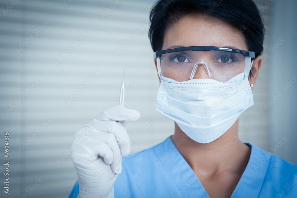 Dentist in surgical mask holding dental tool Dentist in surgical mask holding dental tool