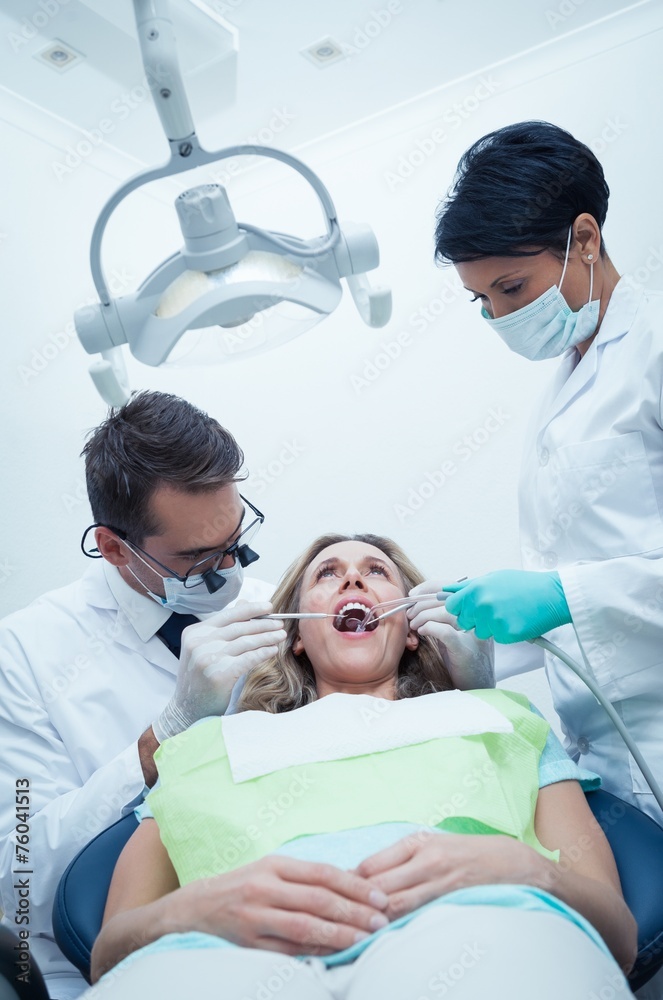 Obraz premium Dentist with assistant examining womans teeth