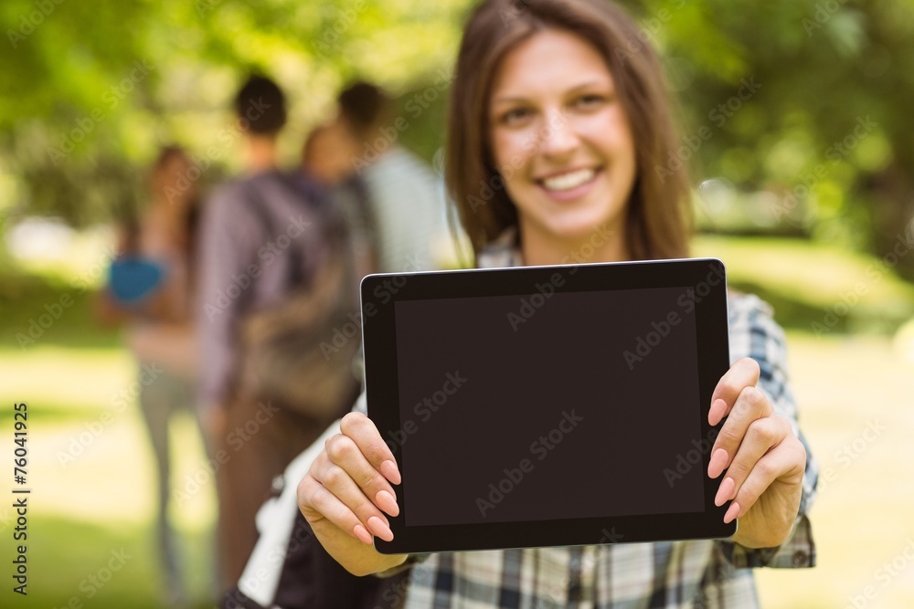Smiling student with a shoulder bag and showing screen at tablet