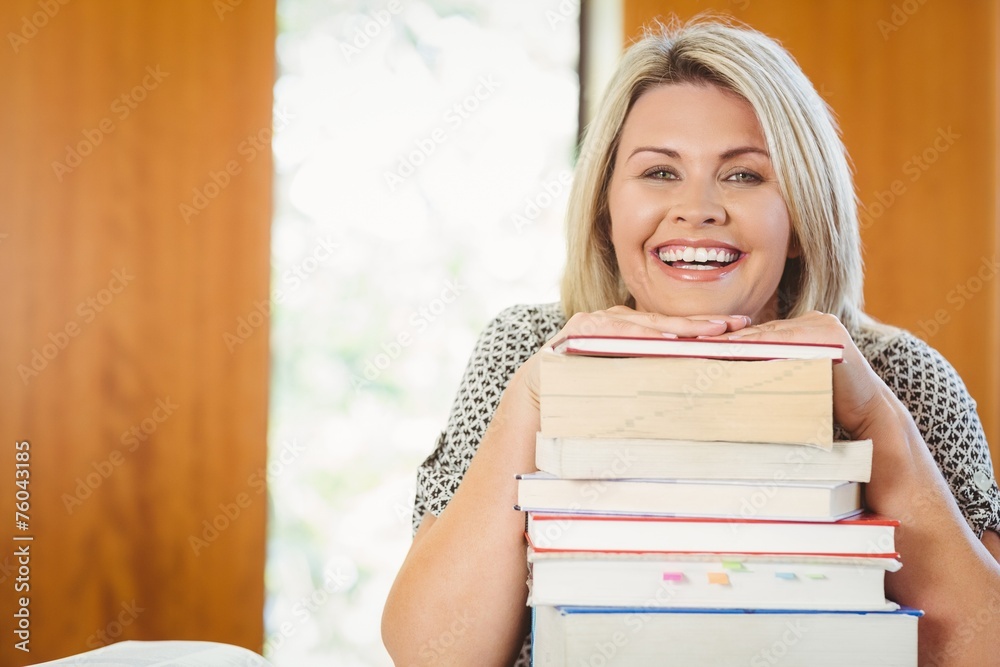 Smiling blonde mature student with stack of books