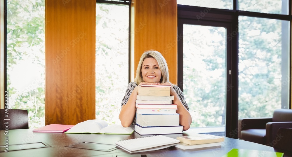 Smiling blonde mature student with stack of books Smiling blonde mature student with stack of books