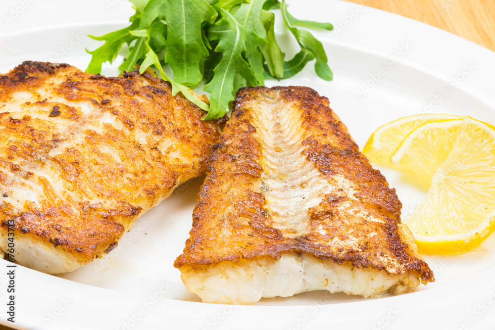 White fish with lemon on white plate