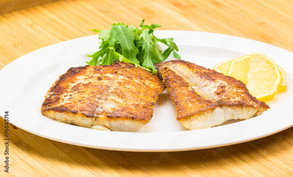 White fish with lemon on white plate