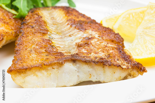 White fish with lemon on white plate