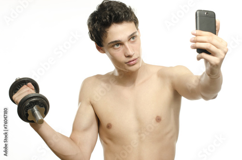 Skinny man taking selfie with phone while training biceps