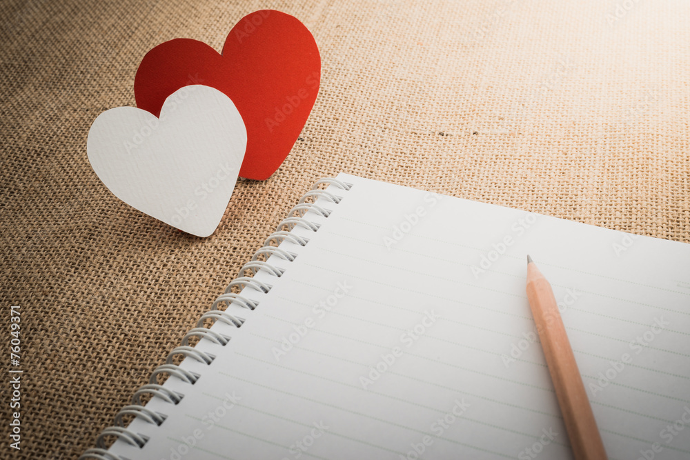 red hearts symbol and notebook on fabric sack surface