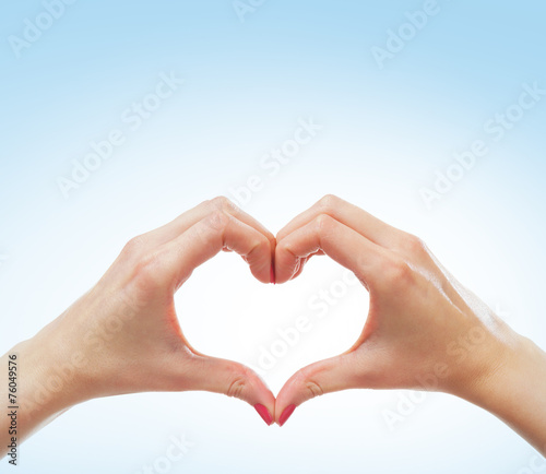 Beautiful female hands in a form of a heart on blue