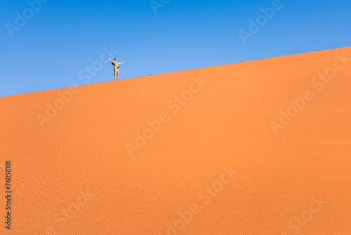 Adventurous man lonely traveler hiking on sand dune at Deadvlei