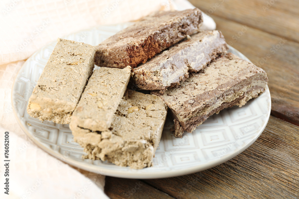 Two kinds of sunflower halva on plate, on wooden background