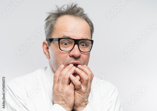 Closeup portrait of a nerdy guy with glasses biting his nails