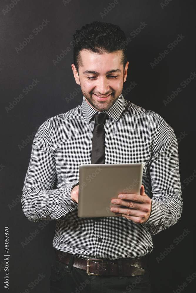 Young Man Typing on Digital Tablet, Black Background Young Man Typing on Digital Tablet, Black Background