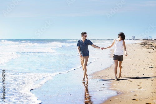 Barefoot young couple walking on a beach