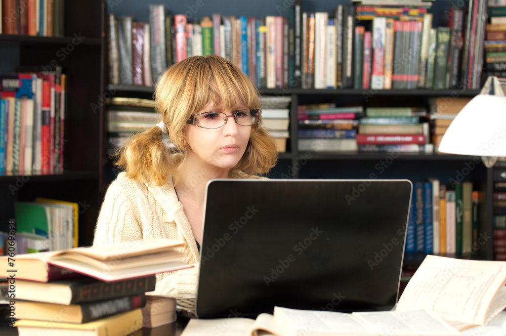 Female student studying in library with a laptop Female student studying in library with a laptop