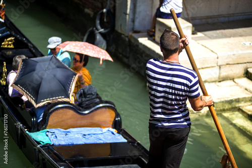 VENICE, ITALY - JULY 12 : Gondolier plying his tradein Venice It