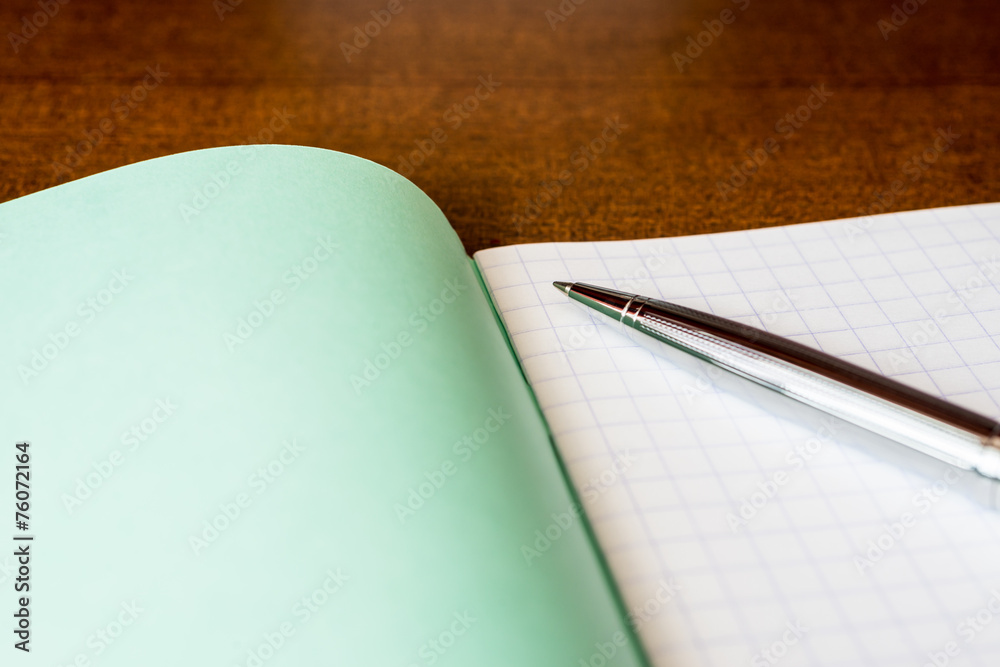 Pen and an exercise book on a wooden table Pen and an exercise book on a wooden table