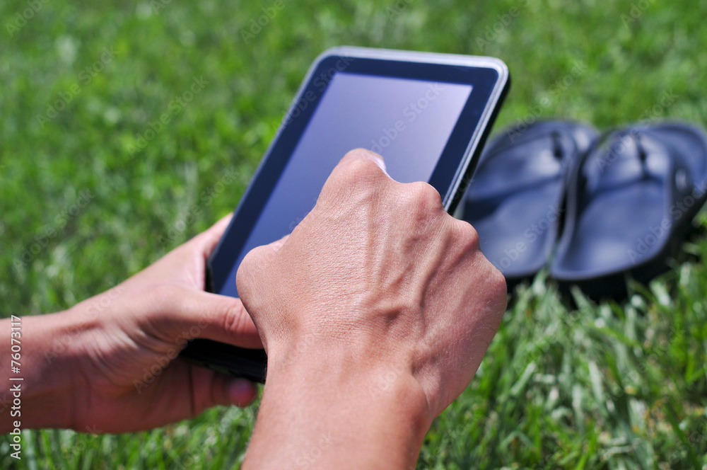 young man using a tablet computer in a park