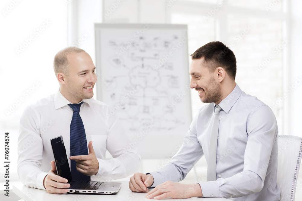 two smiling businessmen with laptop in office two smiling businessmen with laptop in office