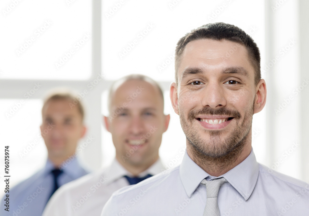 smiling businessman in office with team on back smiling businessman in office with team on back