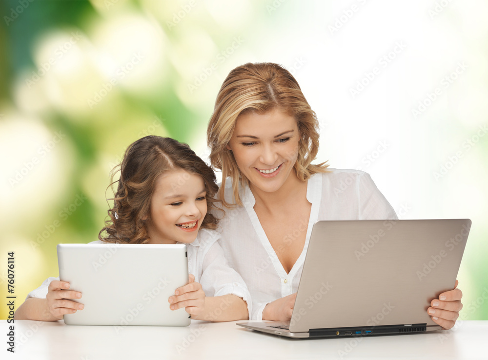 mother with girl looking to laptop and tablet pc mother with girl looking to laptop and tablet pc
