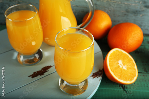 Glass of orange juice with slices on color wooden background