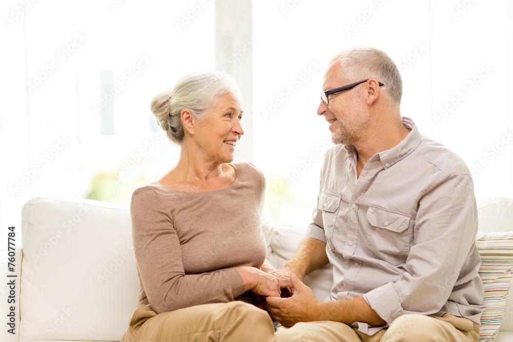 happy senior couple hugging on sofa at home