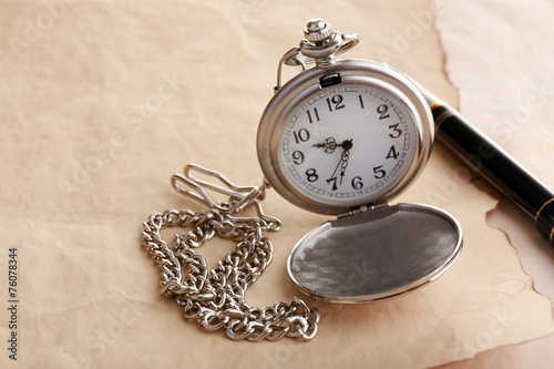 Silver pocket clock on old paper background