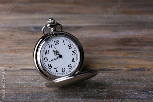 Silver pocket clock on wooden background