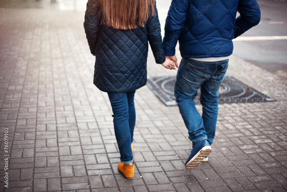 Young couple on a city street walking hand in hand - obrazy, fototapety, plakaty 