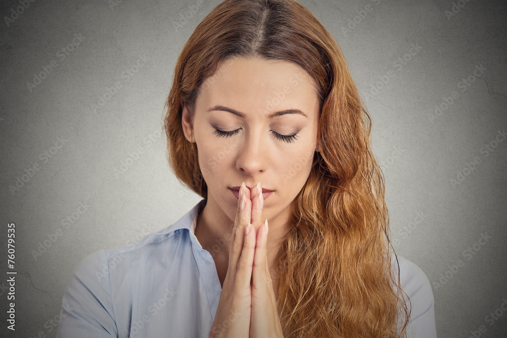 Portrait peaceful woman praying isolated grey wall background Portrait peaceful woman praying isolated grey wall background