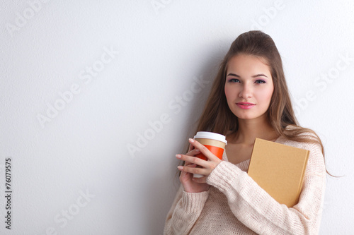 Portrait  a young woman with cup of tea or coffee, holding book