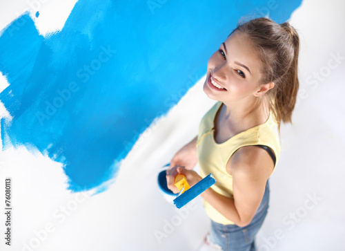 Happy beautiful young woman doing wall painting 