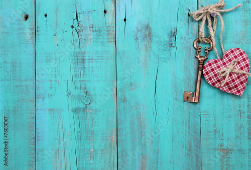 Key and heart hanging on teal blue wood background
