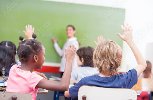 Portrait of children raised their hands in a multi ethnic classr