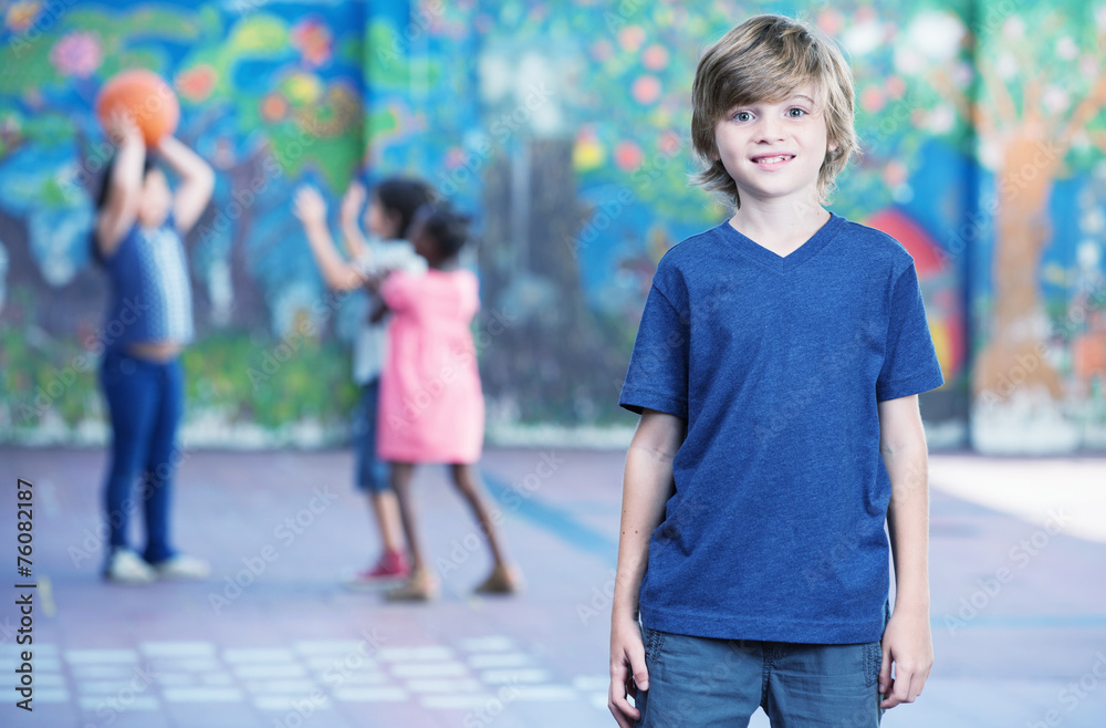 Happy kid smiling in schoolyard with other chilldren playing on Happy kid smiling in schoolyard with other chilldren playing on