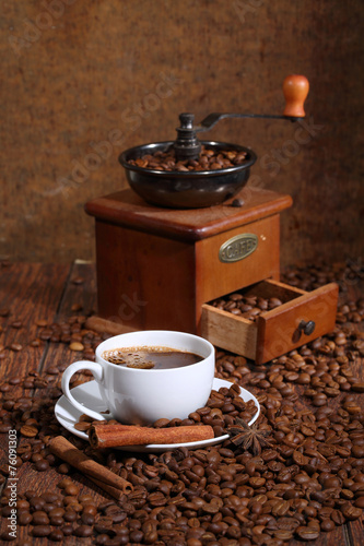 Coffee in a white cup in an environment of coffee grains, cinnam photo