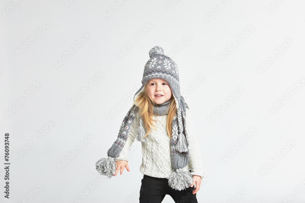 Beautiful blond girl playing in the winter warm hat and scarf on