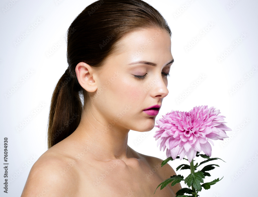 Attractive woman smelling flower over gray background