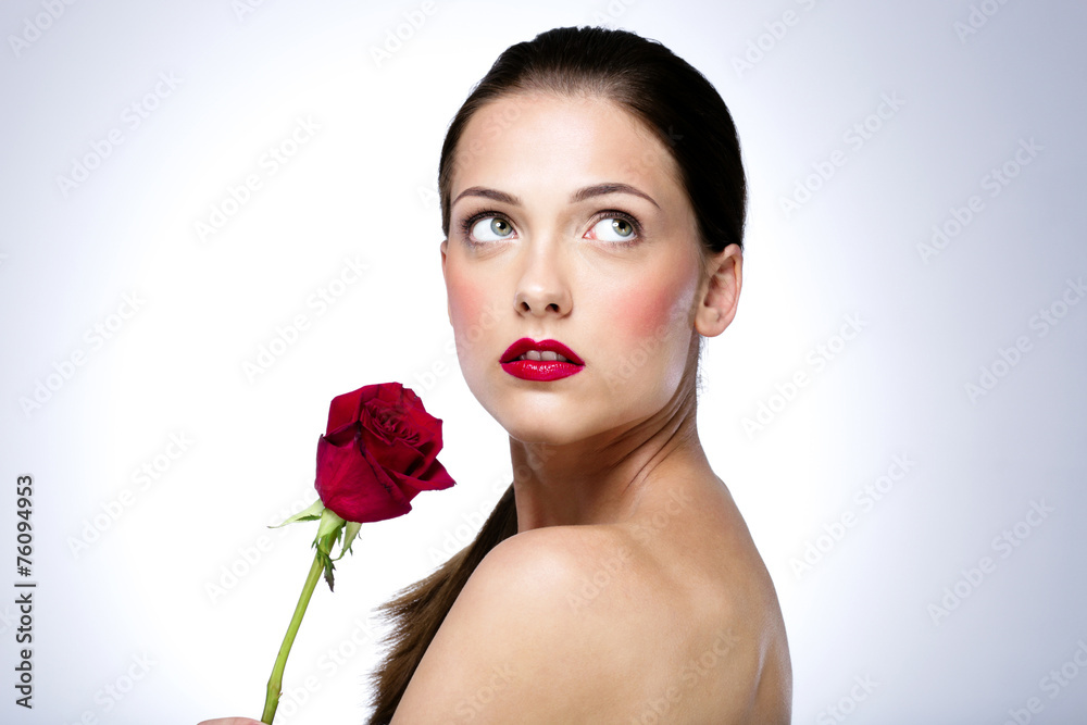 Portrait of a beautiful woman holding red rose and looking up
