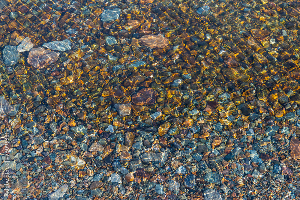 Sea bottom with pebbles through clear water. Winter.