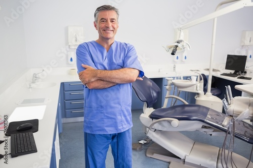 Happy dentist standing with arms crossed